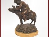 statue en bronze représentant un garçon à dos d'âne, tenant un oiseau dans la main
