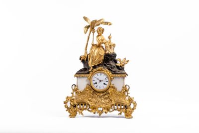 une horloge en or surmontée d'une statue