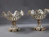 deux vases blancs et dorés ornés de fleurs, posés sur une table