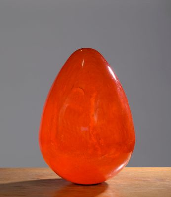 an orange glass vase sitting on a wooden table
