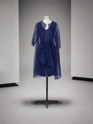 une robe bleue posée sur un mannequin devant un mur blanc
