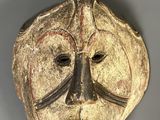 gros plan d'un masque en bois sur une surface grise