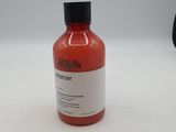 une bouteille contenant un liquide rouge posée sur une surface blanche