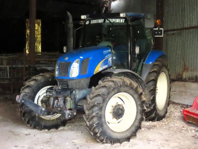 a blue tractor that is parked in a barn