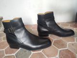 pair of black leather ankle boots with buckles on a tiled floor