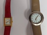 two watches are sitting next to each other on a white surface