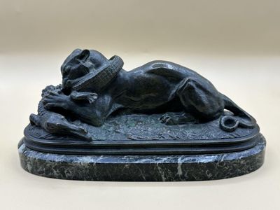 statue d'un chien couché sur un socle en marbre, coiffé d'un chapeau