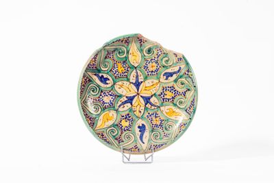 une assiette décorative posée sur un socle, sur une surface blanche
