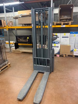 un chariot élévateur dans un entrepôt, avec des palettes au premier plan