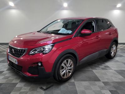 une voiture rouge est garée dans une pièce au sol en damier