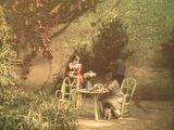 une femme assise à une table dans un jardin
