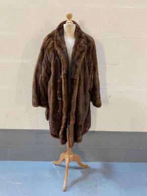 un manteau de fourrure posé sur un mannequin devant un mur blanc