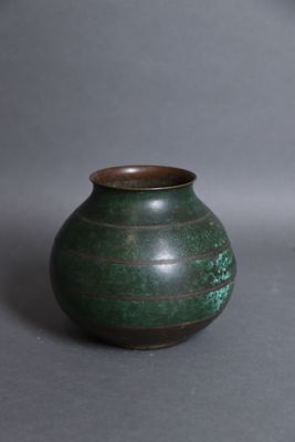 un petit vase vert posé sur une surface grise