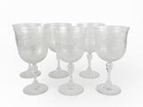 six verres à vin transparents posés les uns à côté des autres sur une surface blanche