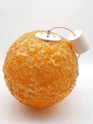 une orange déjà pelée, posée sur une surface blanche