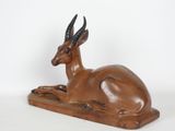 statue of an antelope laying down on a white surface
