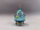 une image représentant un flacon de parfum en verre bleu orné de fleurs