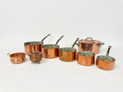 a group of copper pots and pans sitting on a white surface