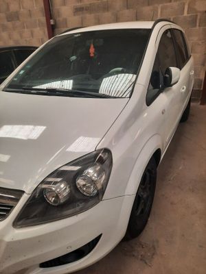 La voiture blanche est garée dans le garage, à côté d'autres voitures.