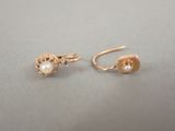 une paire de boucles d'oreilles en or ornées de perles, posée sur une table