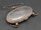 an old silver purse with a chain around it on a black surface