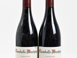 two bottles of red wine sitting next to each other on a white surface