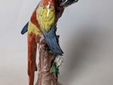 a figurine of a parrot sitting on a tree stump