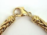 a close up of a gold bracelet on a white surface