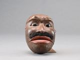 une sculpture en bois représentant un homme avec une moustache sur la tête