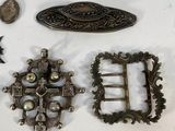 several pieces of antique metal are displayed on a white surface