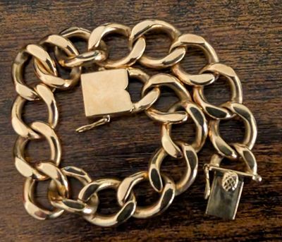a gold chain bracelet with a padlock on top of it
