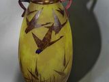 a yellow vase with birds painted on it sitting on a table