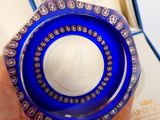 Quelqu'un tient un bol en verre bleu sur lequel est représentée une femme.