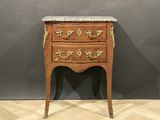 une vieille commode en bois avec un plateau en marbre, posée sur un sol à motif en chevrons