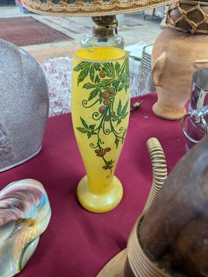 a yellow vase on a table with a lamp on it