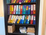 a black bookcase filled with lots of colorful binders