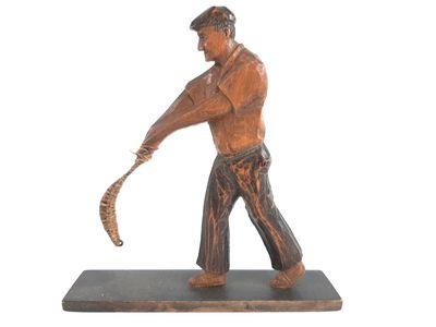 statue d'un homme tenant une batte de baseball, posée sur un socle en bois