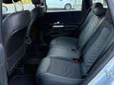 the back seats of a silver car are empty in a parking lot