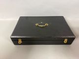 an old black suitcase with a gold handle on a white surface