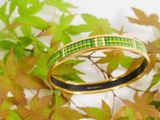 green and black enamel bangle bracelet on a branch of a tree