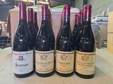 six bouteilles de vin sont alignées sur une table dans un entrepôt