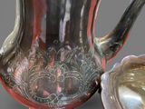 a silver pitcher and a silver spoon sitting on a table