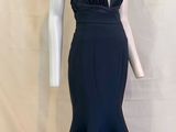 Le mannequin porte une robe noire avec un décolleté en V plongeant.