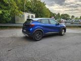 a blue car parked in a parking lot next to a building