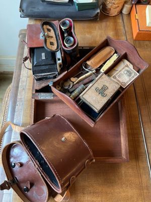 une table en bois sur laquelle est posée une valise remplie d'objets divers