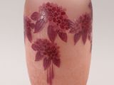 a pink vase with purple flowers on it on a white background
