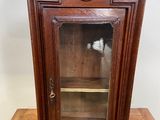 une vieille armoire en bois avec une porte vitrée, posée sur une table en bois