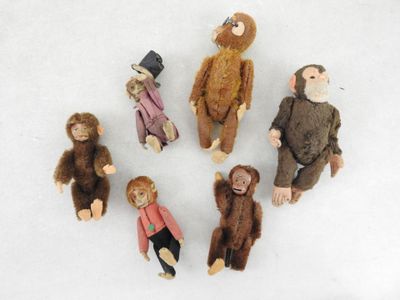 cinq peluches assises en cercle sur une surface blanche