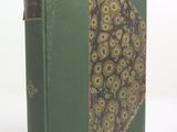 un vieux livre à la couverture verte ornée d'un motif