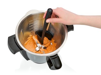une personne qui remue un plat dans une casserole à l'aide d'une pince